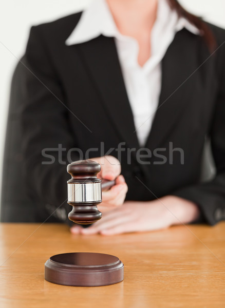 Young woman using a gavel while sitting at a desk against a white background Stock photo © wavebreak_media
