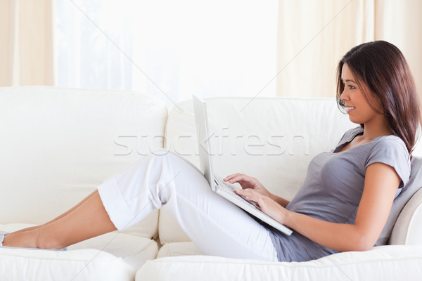  woman sitting  on sofa in her livingroom with notebook on her lap Stock photo © wavebreak_media
