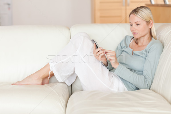 Fiatal nő kanapé gépel okostelefon telefon mobil Stock fotó © wavebreak_media