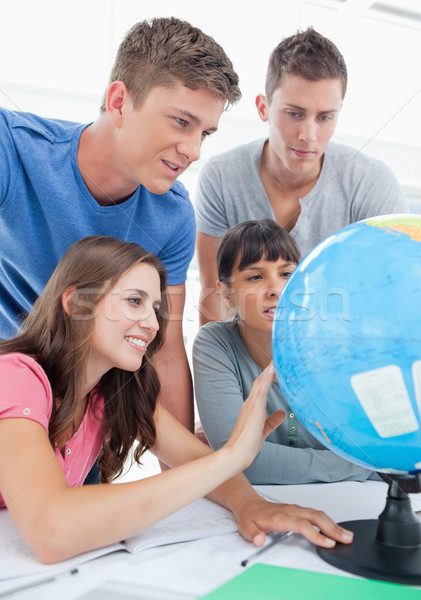 A close up shot of four people sitting in front of the globe and looking for a place  Stock photo © wavebreak_media