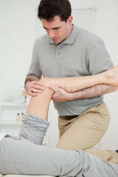 Serious physiotherapist looking at the knee of a patient in a room Stock photo © wavebreak_media