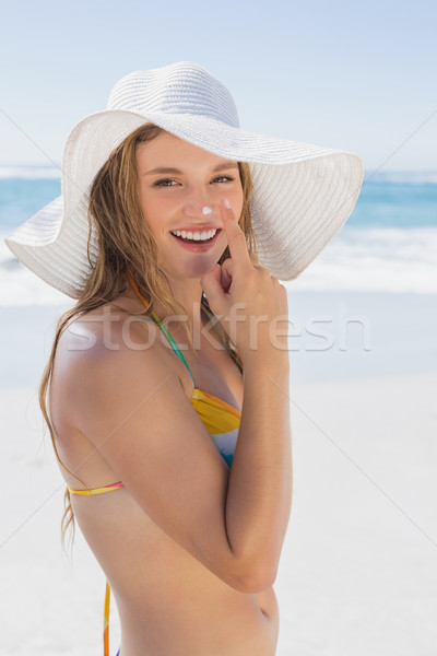 Beautiful girl putting spf on nose on the beach smiling at camer Stock photo © wavebreak_media