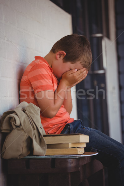 Unhappy boy covering face with hands while sitting on bench Stock photo © wavebreak_media