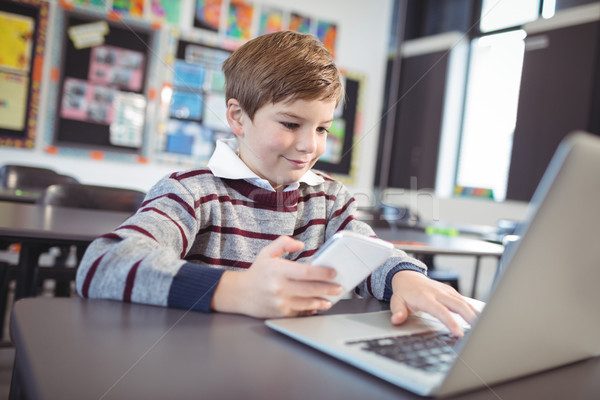 Lächelnd Schüler mit Laptop Handy Schreibtisch Klassenzimmer Stock foto © wavebreak_media