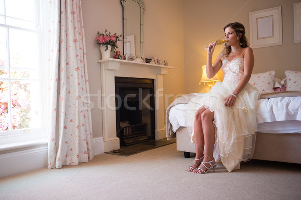 Stock photo: Bride drinking champagne while sitting on bed