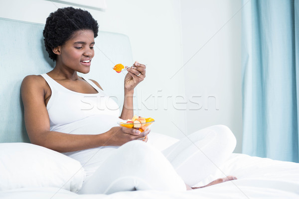 Mujer embarazada comer ensalada de fruta casa embarazadas cama Foto stock © wavebreak_media