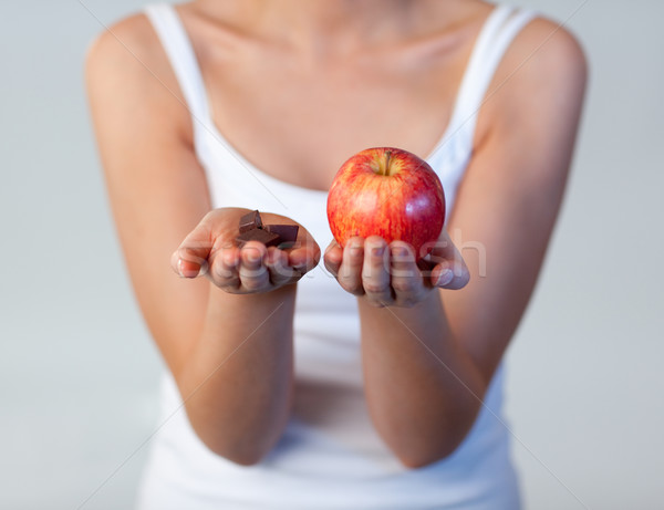 Stock photo: Woman showing chocolate and apple focus on chocolate 