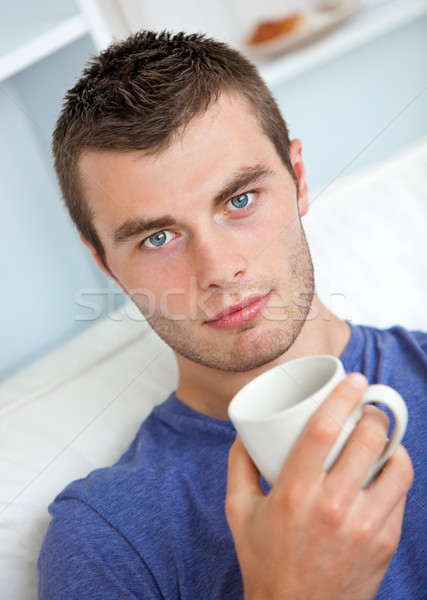 Portrait of a serious young man looking at the camera holding a cup in the living-room Stock photo © wavebreak_media