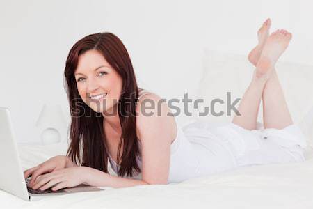 Femeie zambitoare pat dormitor picioare faţă sexy Imagine de stoc © wavebreak_media
