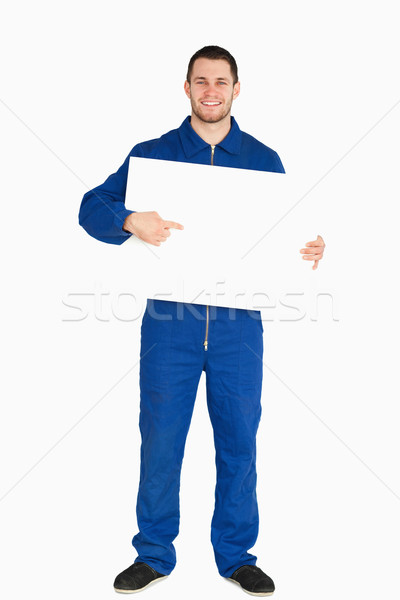 Smiling young mechanic in boiler suit pointing on banner in his hands against a white background Stock photo © wavebreak_media