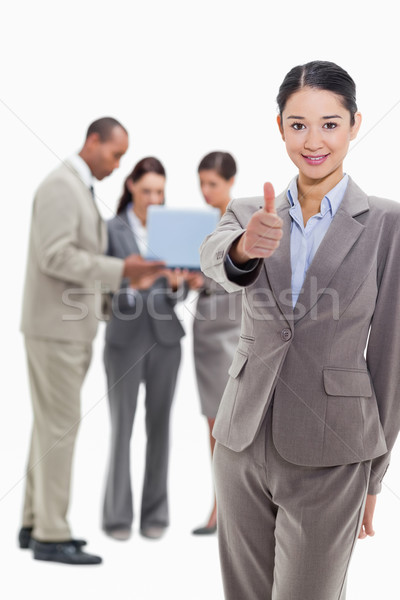Businesswoman smiling and approving with co-workers watching a laptop in the background Stock photo © wavebreak_media