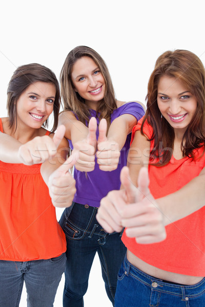 Stock photo: Teenagers putting their thumbs up while standing against a colourless background