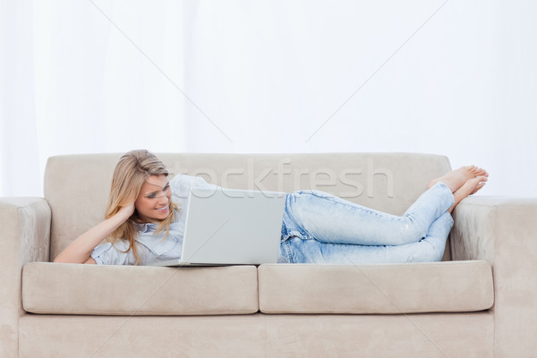 Femme souriante canapé tête main utilisant un ordinateur portable [[stock_photo]] © wavebreak_media
