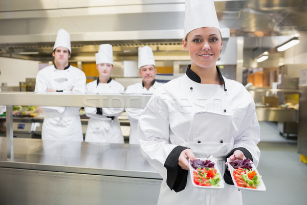 Chef presenting two salads in kitchen with team standing behind her Stock photo © wavebreak_media