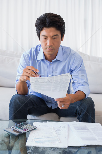 Stock photo: Man sitting on couch working out his finances