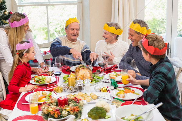 Grandfather in party hat carving chicken during dinner Stock photo © wavebreak_media