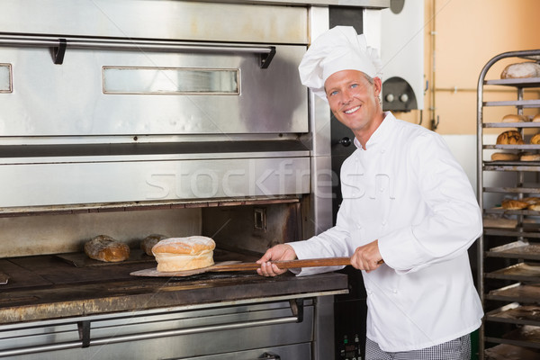 Happy baker taking out fresh loaf Stock photo © wavebreak_media