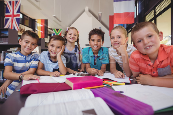 Portrait of happy schoolkids studying at table in library Stock photo © wavebreak_media