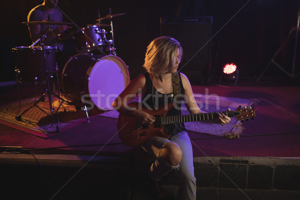 Stock photo: guitarist practicing while sitting on stage in nightclub