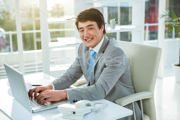 Smiling asian businessman using his computer Stock photo © wavebreak_media