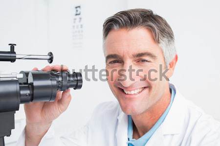 Optometrist looking through biomicroscope Stock photo © wavebreak_media