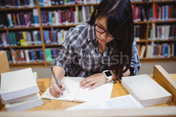 Vrouwelijke student schrijven merkt bibliotheek bureau Stockfoto © wavebreak_media