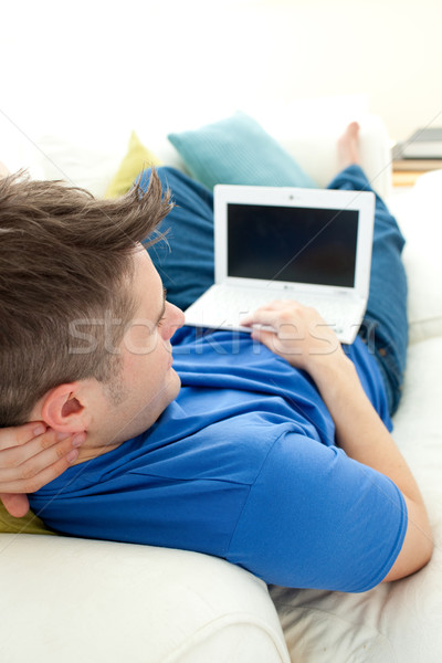 Charming manusing a laptop on a sofa Stock photo © wavebreak_media