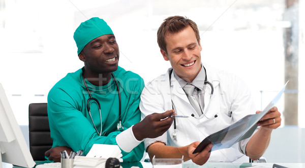 Young doctor and surgeon looking at a x-ray sitting at a desk Stock photo © wavebreak_media