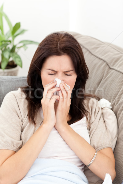 Portrait of a sick woman blowing her nose on the sofa at home Stock photo © wavebreak_media