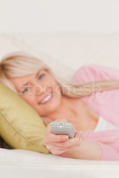 Beautiful blonde woman posing while lying on a sofa in the living room Stock photo © wavebreak_media