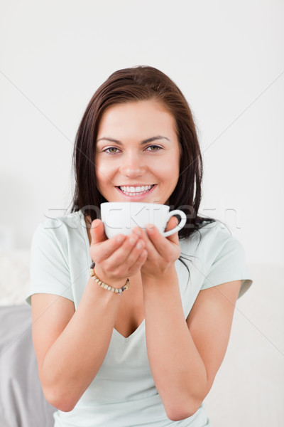 Portrait of a smiling dark-haired woman drinking tea against a white background Stock photo © wavebreak_media