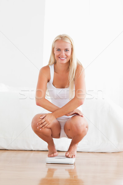 Portrait of a woman squatting on a weighing machine looking at the camera Stock photo © wavebreak_media