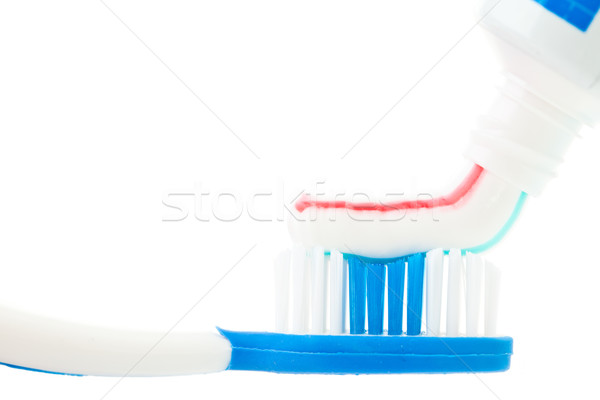 Close up of a tube of toothpaste with a toothbrush against white background Stock photo © wavebreak_media