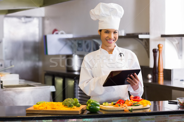 Smiling chef using digital tablet while cutting vegetables Stock photo © wavebreak_media