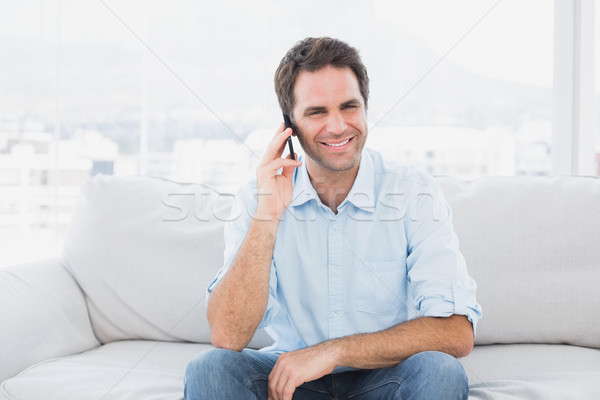 Heureux homme séance canapé téléphone [[stock_photo]] © wavebreak_media