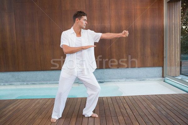 Stock photo: Handsome man in white doing tai chi