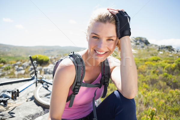 Fit pretty cyclist taking a break on rocky peak smiling at camer Stock photo © wavebreak_media