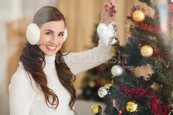 Smiling brunette holding heart near a christmas tree Stock photo © wavebreak_media