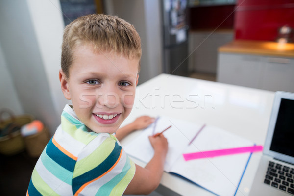 Smiling boy doing his homework in kitchen Stock photo © wavebreak_media