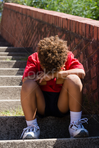 Upset boy sitting on staircase in the boot camp Stock photo © wavebreak_media