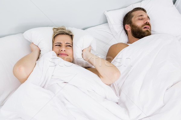  Woman covering ears while man snoring on bed Stock photo © wavebreak_media