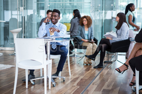 Businessman talking on mobile phone while having coffee in office Stock photo © wavebreak_media