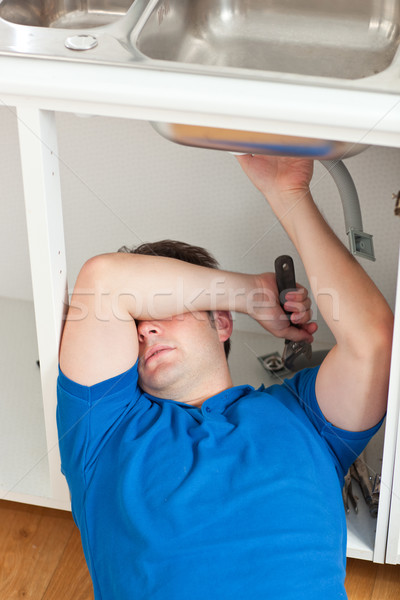 Tired man repairing his sink in the kitchen at home Stock photo © wavebreak_media