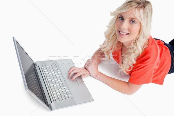 Souriant jeune femme utilisant un ordinateur portable couché blanche sourire [[stock_photo]] © wavebreak_media