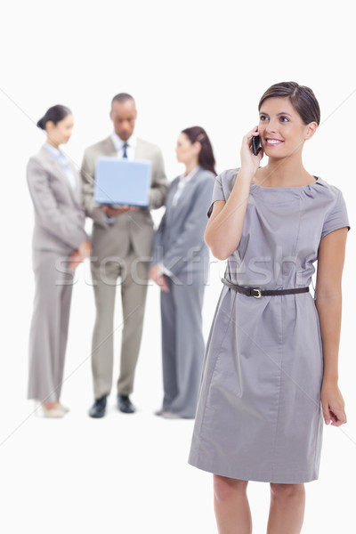 Businesswoman smiling on the phone with one arm along her body and co-workers in the background look Stock photo © wavebreak_media