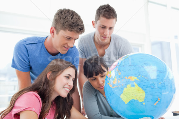 A group of students smile while searching the globe for a country Stock photo © wavebreak_media