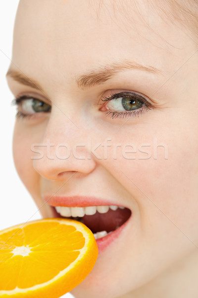 Close up of a woman placing a slice of orange in her mouth against white background Stock photo © wavebreak_media