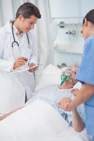 Doctor looking at patient next to a nurse in hospital ward Stock photo © wavebreak_media
