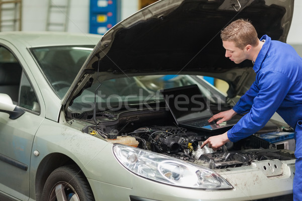 Mechanic with laptop checking engine Stock photo © wavebreak_media