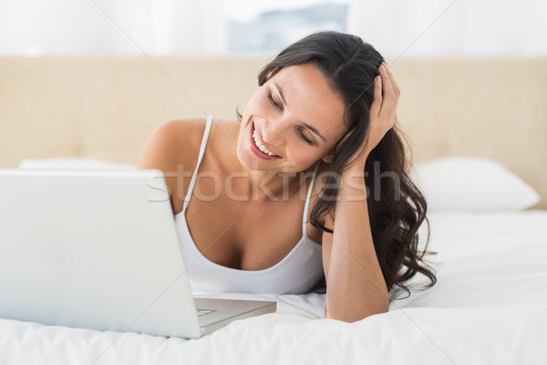 Fericit bruneta folosind laptop acasă dormitor calculator Imagine de stoc © wavebreak_media